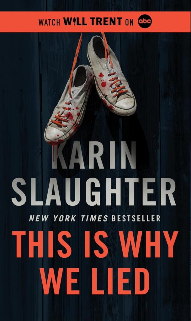 Bloody shoes hang from somewhere off the cover. They dangle down a dark background of wood planks by orange shoe strings. Watch Will Trent on ABC is at the top of the book. At the bottom is Karin Slaughter. New York Times Bestseller and This is Why We Lied.